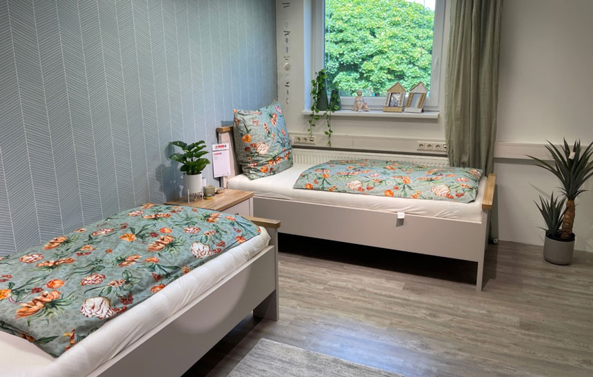 Kinderzimmer mit zwei Betten und Blumenbettwäsche.