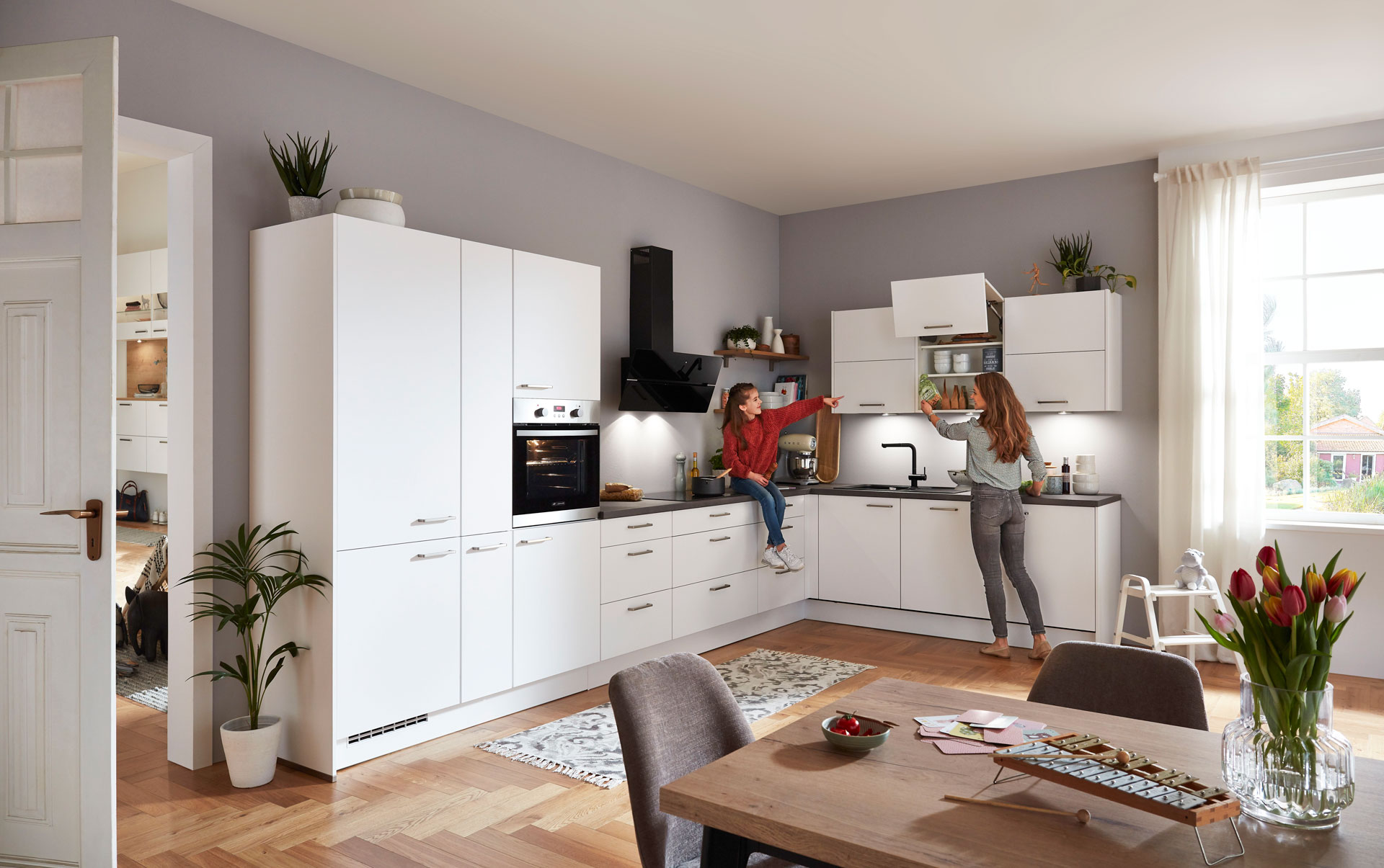 Moderne Eckküche in Weiß mit dunkler Arbeitsplatte und Hängeschrank mit Falt-Lifttüren